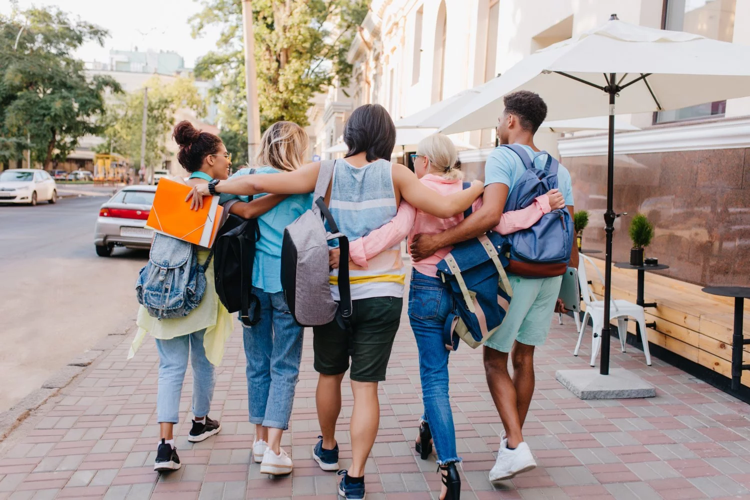 20260902151838_portrait-from-back-students-with-stylish-backpacks-walking-down-street-after-lectures-university-tall-brunette-young-man-embracing-girls-while-spending-time-with-them-outdoot.jpg